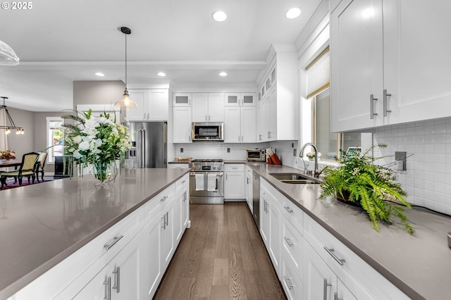 kitchen featuring high end appliances, a sink, decorative light fixtures, recessed lighting, and white cabinets