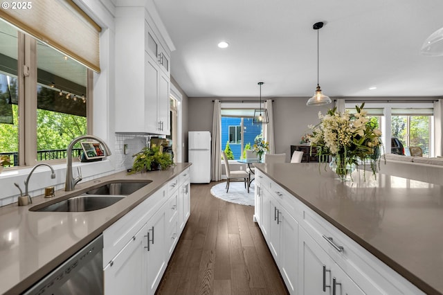 kitchen featuring freestanding refrigerator, a sink, dishwasher, plenty of natural light, and recessed lighting