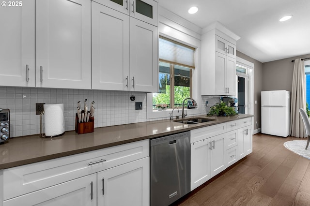 kitchen with dishwasher, freestanding refrigerator, a sink, dark wood-style flooring, and white cabinets