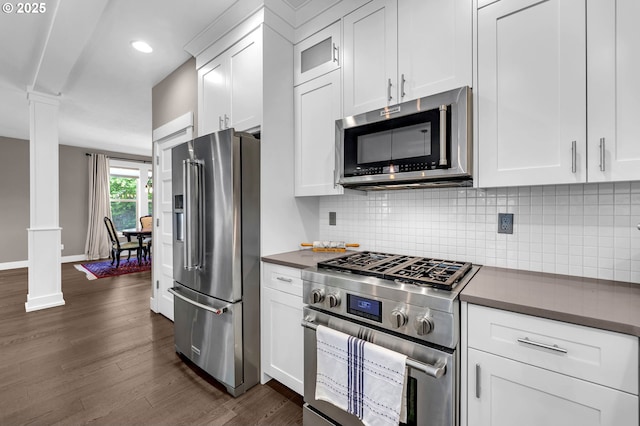kitchen featuring high quality appliances, decorative columns, dark countertops, white cabinetry, and dark wood finished floors