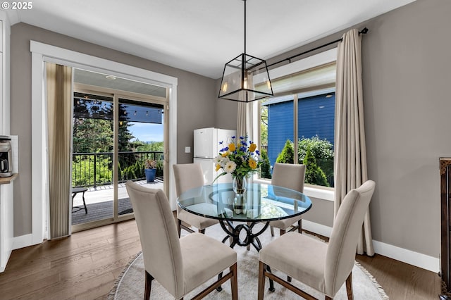 dining room featuring healthy amount of natural light, wood finished floors, and baseboards