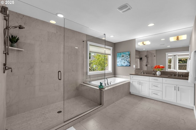 full bath featuring plenty of natural light, a stall shower, a bath, double vanity, and recessed lighting