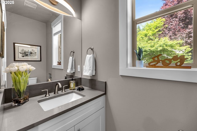 half bathroom with healthy amount of natural light, toilet, and vanity