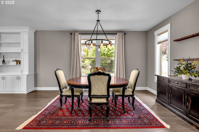 dining space featuring a chandelier, wood finished floors, baseboards, and a textured ceiling