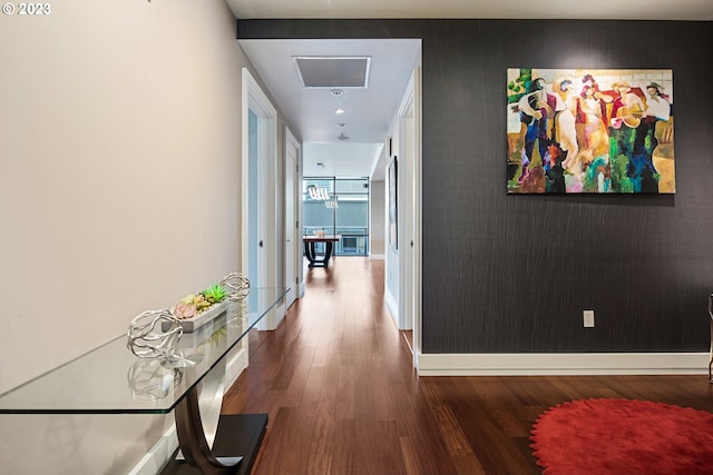 corridor with visible vents, wood finished floors, baseboards, and an accent wall
