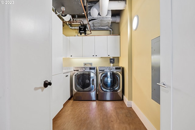 clothes washing area with washing machine and clothes dryer, cabinet space, and baseboards