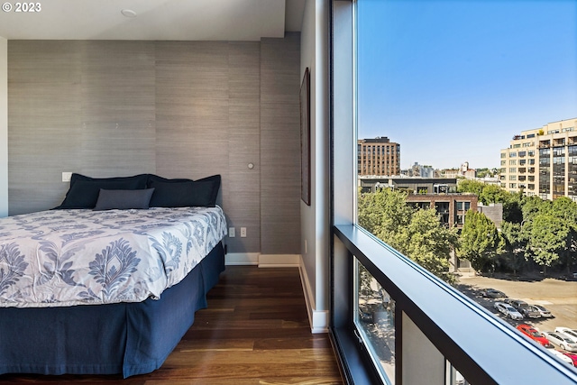 bedroom featuring baseboards, a view of city, and wood finished floors