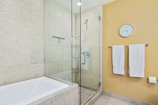 bathroom featuring a shower stall, baseboards, tile patterned floors, and a garden tub