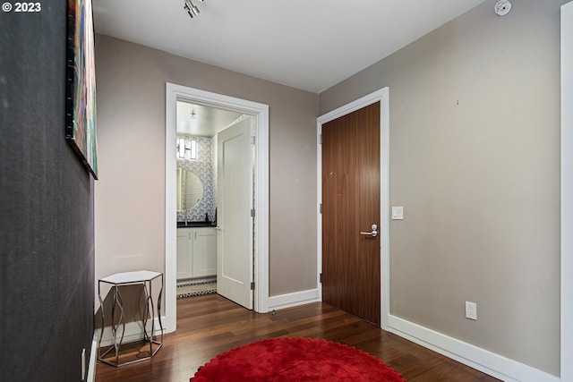 interior space with ensuite bath, baseboards, and wood finished floors