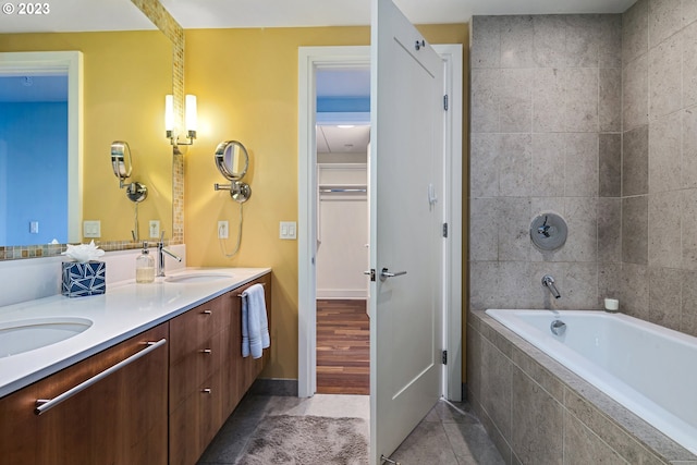 full bathroom featuring tile patterned floors, double vanity, tiled bath, and a sink