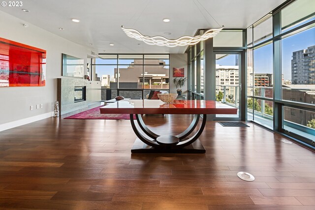 game room featuring expansive windows, a city view, a high end fireplace, and wood finished floors