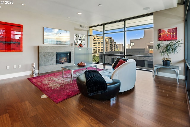living area featuring baseboards, a fireplace, visible vents, and wood finished floors