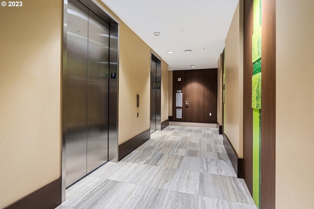 corridor with baseboards, elevator, and recessed lighting