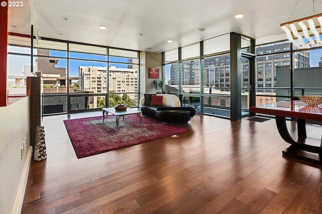 living area with a fireplace, a city view, wood finished floors, and floor to ceiling windows