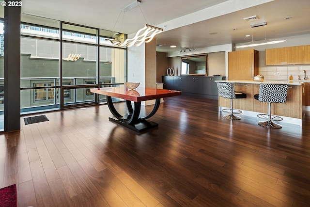 dining area featuring a healthy amount of sunlight, an inviting chandelier, expansive windows, and dark wood-type flooring