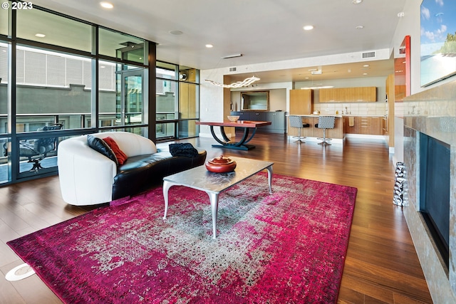 living area featuring wood finished floors, a fireplace, visible vents, floor to ceiling windows, and recessed lighting