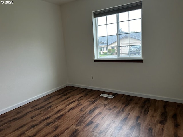 spare room with a wealth of natural light and dark wood-type flooring