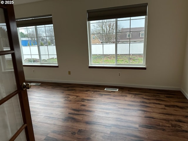 spare room with dark hardwood / wood-style flooring and plenty of natural light