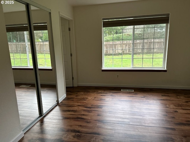 empty room featuring plenty of natural light and dark wood-type flooring