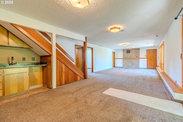 975 SW Florence Ct, Gresham, OR 97080 - unfurnished living room featuring light colored carpet, stairs, a textured ceiling, a sink, and baseboards