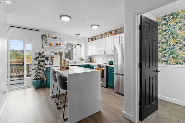 kitchen featuring appliances with stainless steel finishes, open shelves, light countertops, white cabinets, and plenty of natural light