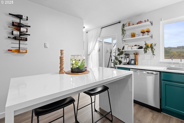 kitchen with stainless steel dishwasher, a kitchen breakfast bar, open shelves, light wood-type flooring, and a sink
