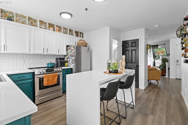 kitchen featuring stainless steel appliances, light countertops, a breakfast bar area, white cabinets, and wood finished floors