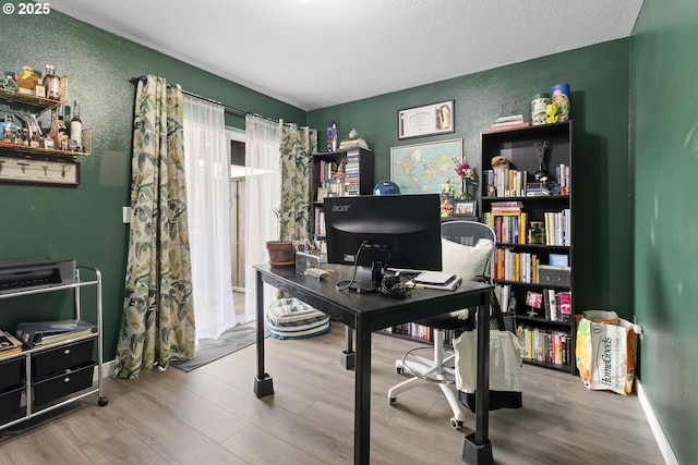 office featuring wood finished floors, a textured wall, and a textured ceiling