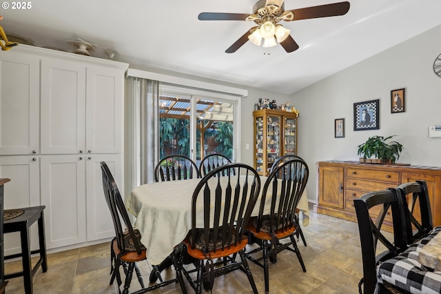 dining room featuring lofted ceiling, stone finish flooring, and ceiling fan