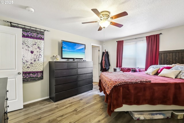 bedroom with a textured ceiling, baseboards, wood finished floors, and a ceiling fan