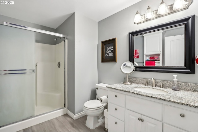 full bathroom featuring a stall shower, vanity, toilet, and wood finished floors