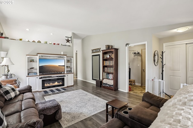 living area featuring vaulted ceiling, dark wood-style flooring, and baseboards