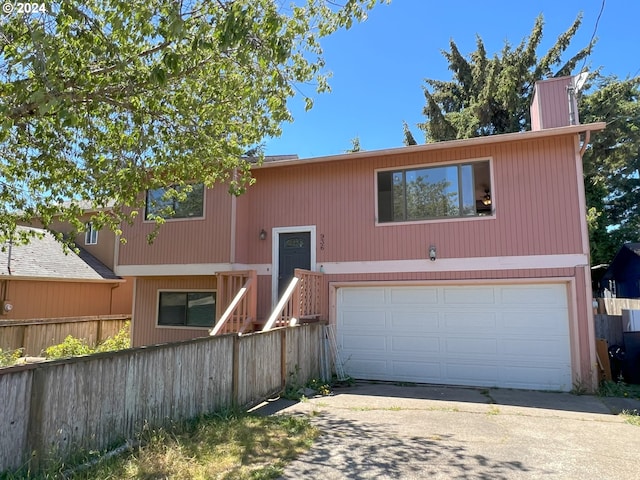 bi-level home with driveway, an attached garage, and fence