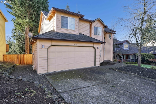 view of front facade with a garage, driveway, fence, and roof with shingles