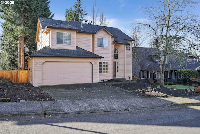 traditional-style house with aphalt driveway, an attached garage, fence, and roof with shingles