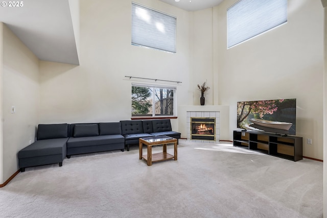 carpeted living room with a high ceiling, a fireplace, and baseboards