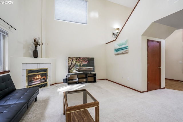 living room featuring a high ceiling, a fireplace, carpet flooring, and baseboards