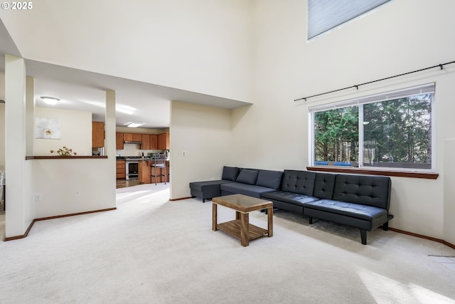 living room with light carpet, a high ceiling, and baseboards