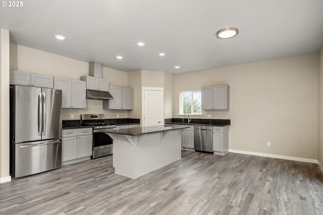1516 Samuel Dr, Cottage Grove, OR 97424 - kitchen with appliances with stainless steel finishes, under cabinet range hood, a breakfast bar, a center island, and light wood-type flooring
