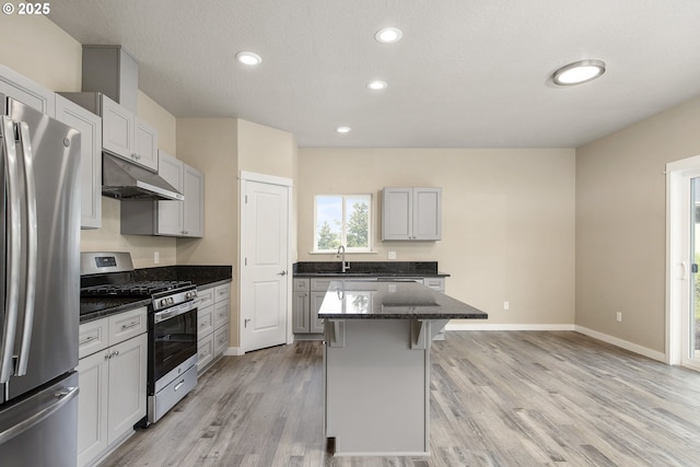 1516 Samuel Dr, Cottage Grove, OR 97424 - kitchen with stainless steel appliances, under cabinet range hood, a breakfast bar, light wood finished floors, and a center island