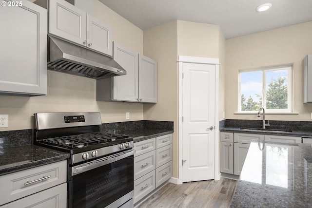 1516 Samuel Dr, Cottage Grove, OR 97424 - kitchen featuring under cabinet range hood, stainless steel gas stove, a sink, light wood-type flooring, and dark stone countertops