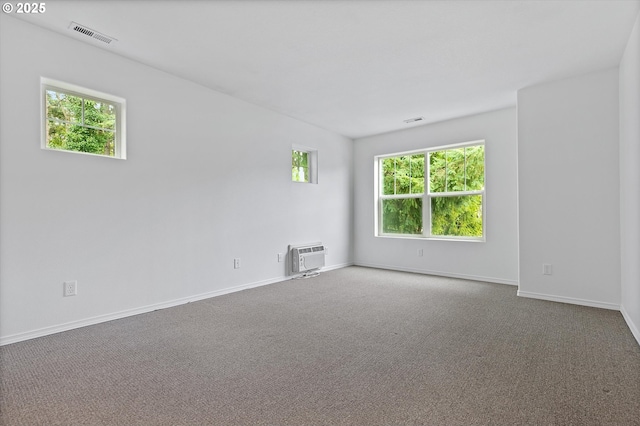 spare room with carpet flooring, an AC wall unit, and a wealth of natural light