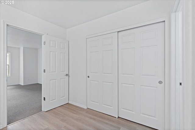 unfurnished bedroom featuring light hardwood / wood-style flooring and a closet