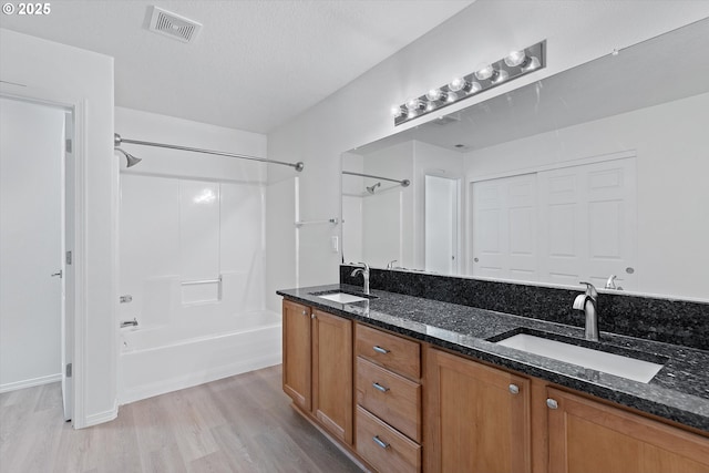 bathroom with bathing tub / shower combination, hardwood / wood-style floors, vanity, and a textured ceiling