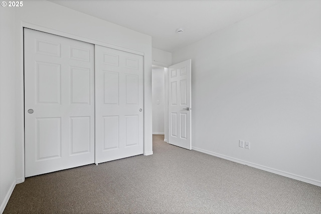 unfurnished bedroom with dark carpet and a closet