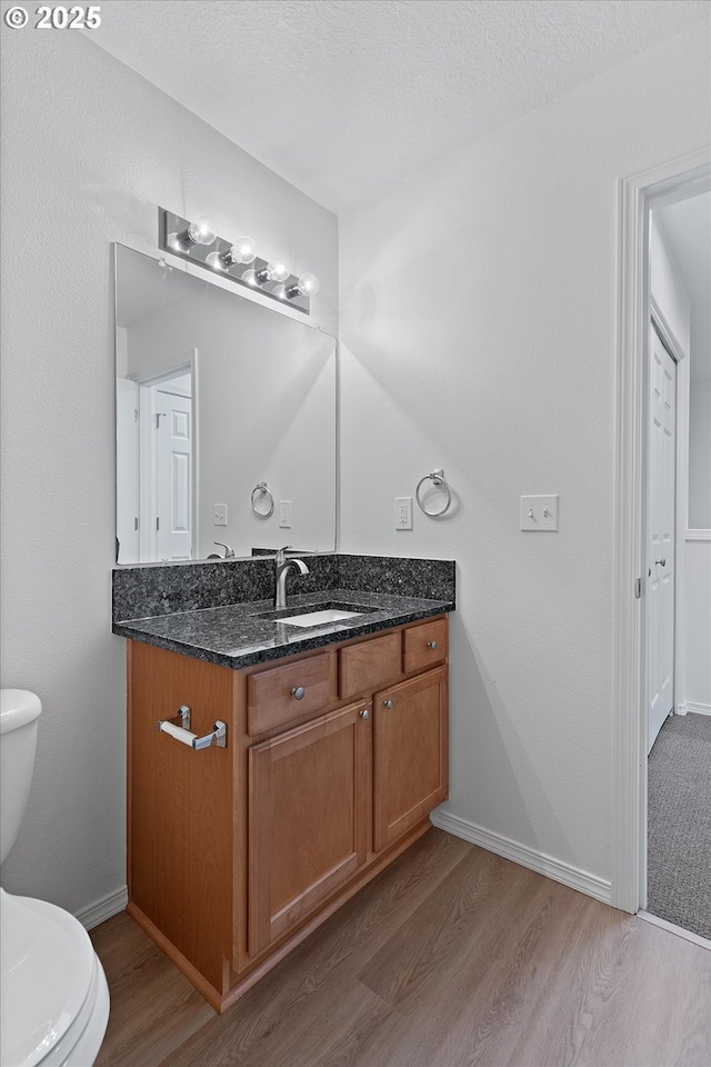 bathroom featuring wood-type flooring, vanity, a textured ceiling, and toilet