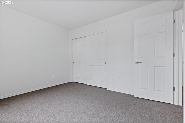 unfurnished bedroom with dark colored carpet and a closet