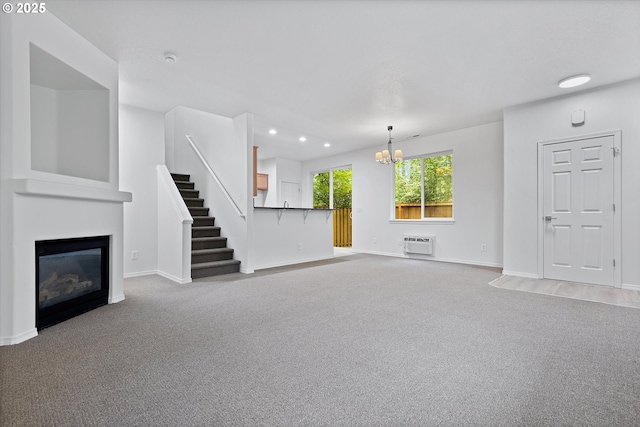 unfurnished living room with carpet flooring, an AC wall unit, and an inviting chandelier