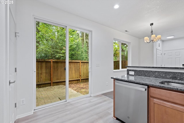 kitchen featuring dishwasher, hanging light fixtures, dark stone counters, a chandelier, and light hardwood / wood-style floors