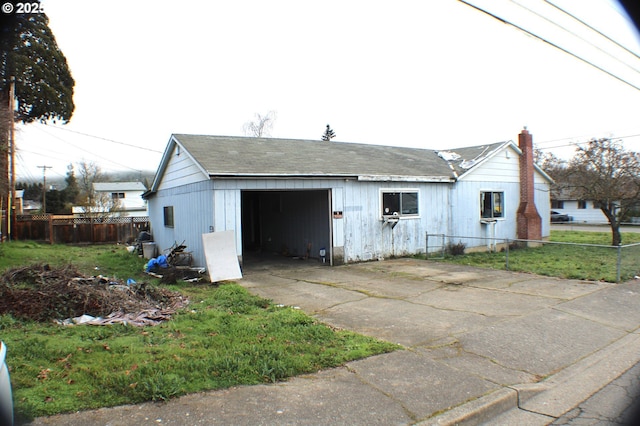 exterior space featuring a garage, concrete driveway, a lawn, and fence